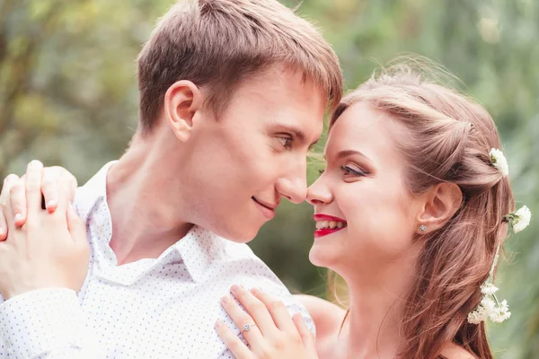 Jovem feliz casal recém-casado tocando narizes no parque.Segurando um bou — Fotografia de Stock