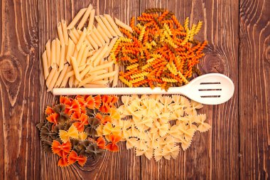 Makarna, retro ahşap zemin üzerine bir tahta kaşık etrafında yalan farklı türleri