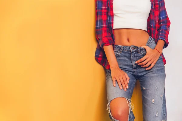 Jonge vrouwen in jeans en een heldere geruite stend, op een gele backg — Stockfoto