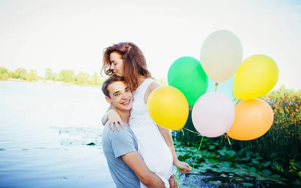 Lovely merry happy couple with balloons looking to each other ne — Stock Photo, Image