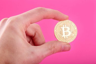 Altın Bitcoin, pembe arka plan tutan adamın el