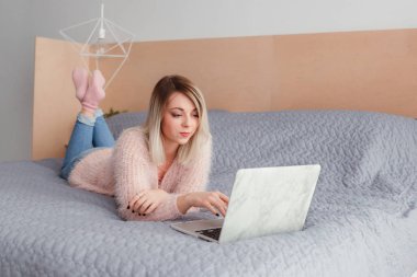 Şoförünün yatakta yatan bir dizüstü bilgisayar üzerinde çalışan mutlu rahat güzel kadın