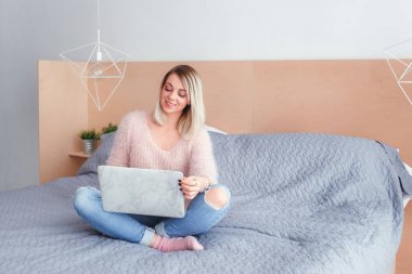 Şoförünün yatakta oturup bir dizüstü bilgisayar üzerinde çalışan mutlu rahat güzel kadın