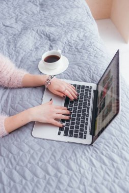 Onun yatağında evde kahve içme ve onu laptop kontrol genç kadın