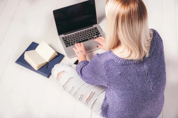 Back view of a woman working behind laptop on the floor