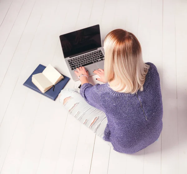 Back view of a woman working behind laptop on the floor