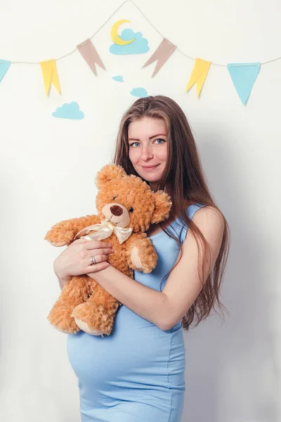 Mujer esperando un bebé con un lindo oso de peluche marrón — Foto de Stock