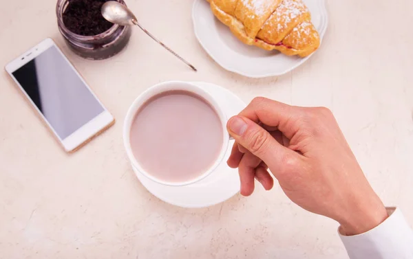 Croissant with raspberry jam, in hand a mug with cocoa, on the t — Stock Photo, Image