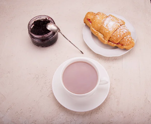 Croissant con mermelada de frambuesa, sobre la mesa un teléfono móvil y co — Foto de Stock