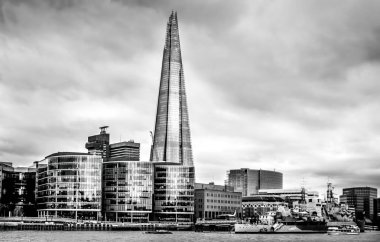 London, 2017 march, United Kingdom: View from the north shore of the Thames Historic HMS Belfast cruiser anchored river Thames with skyscraper Shard in the background on a cloudy March day in London clipart