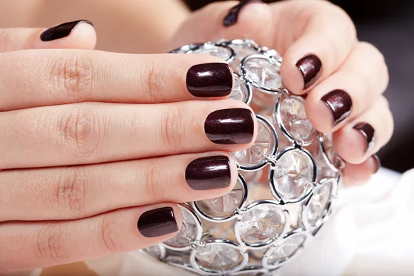 Handen met gemanicuurde nagels gekleurd met donkere paarse nagellak — Stockfoto