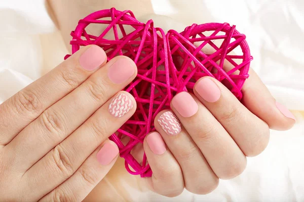 Pembe mat manikürlü tırnaklar bir kalp tutan eller