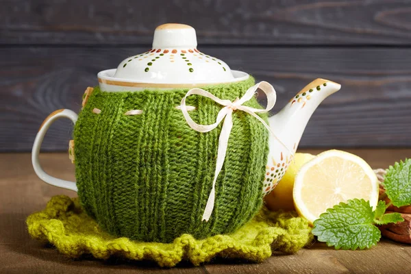 Teapot with handmade knitted cover, lemon, cinnamon, mint — Stock Photo, Image