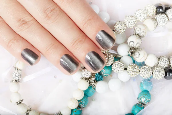 Hand with gray metallic manicured nails and colorful bracelets — Stock Photo, Image