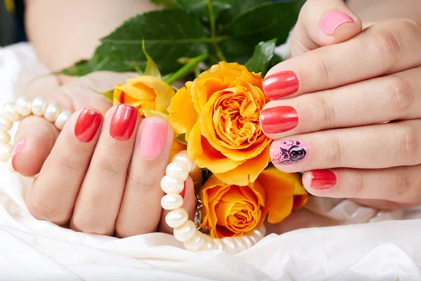 Mãos com unhas curtas manicured colorido com rosa e vermelho unha polonês — Fotografia de Stock