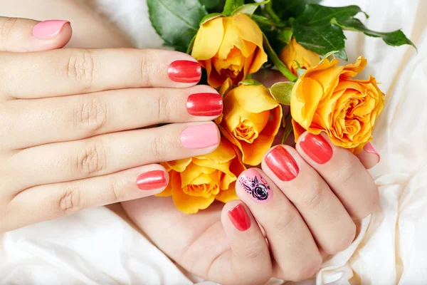 Руки с короткими ухоженными ногтями окрашены в розовый и красный лак для ногтей — стоковое фото