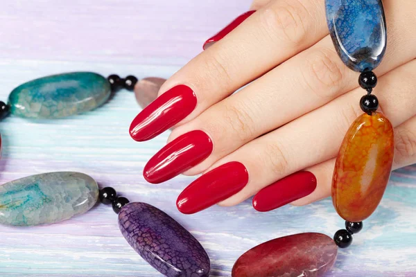 Hand with long artificial manicured nails colored with red nail polish — Stock Photo, Image