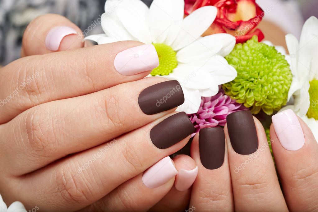 Hands with pink and purple manicured nails holding a bouquet of flowers