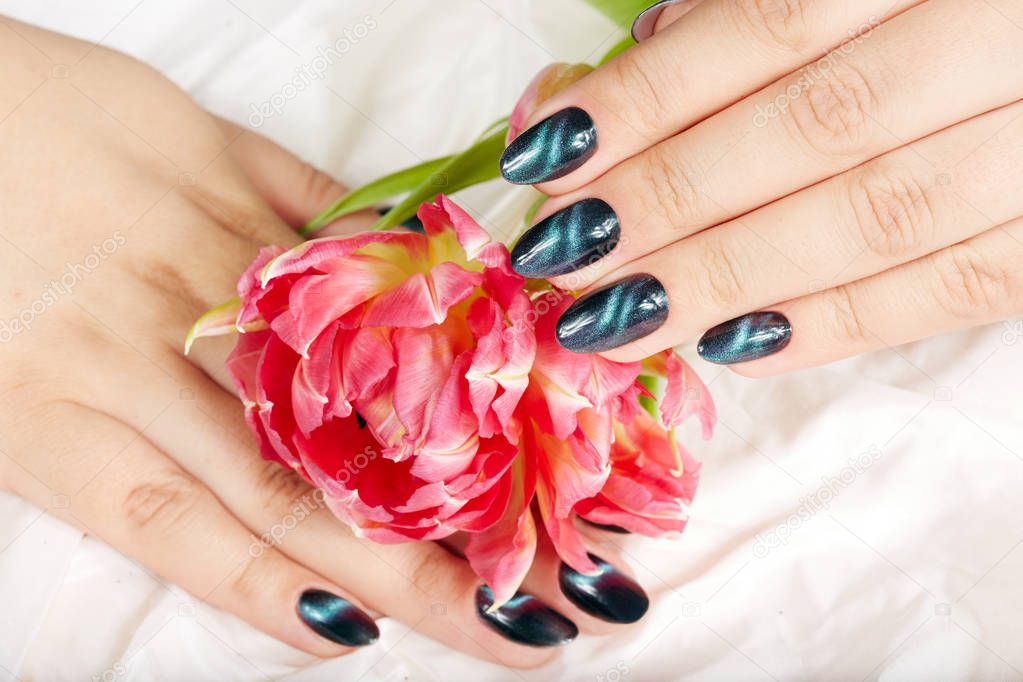 Hands with manicured nails with cat eye design holding a bouquet of flowers