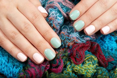 Elleri pembe ve yeşil oje ile renkli kısa manikürlü tırnaklar 