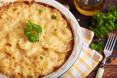 Patates graten. Krem soslu, sarımsaklı ve peynirli maydanozla süslenmiş patates dilimleri. Kırsal tarzda. Vejetaryen yemeği..