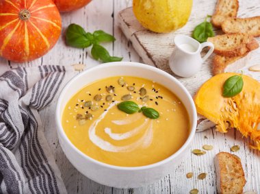Bir kase kabak ve havuç kremalı çorba tohum ve fesleğen yaprağı. Vejetaryen ev yemeği.. 