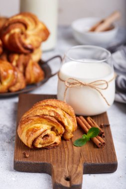 Kahverengi şeker ve tarçınlı maya hamurundan çörekler. Lezzetli ev yapımı tatlı ve bir bardak süt.. 