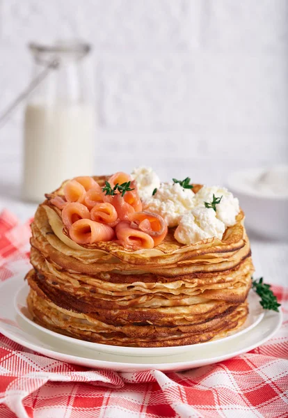 Thin crepe pancakes with salmon fish, cream cheese and thyme. Traditional Russian cuisine. Crepe week. Maslenitsa.
