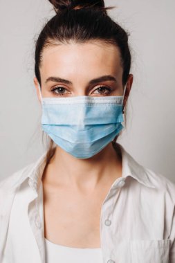 Beyaz arka planda enfeksiyonu önlemek için hijyenik maske takan genç bir kadın portresi..