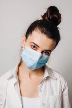 Beyaz arka planda enfeksiyonu önlemek için hijyenik maske takan genç bir kadın portresi..