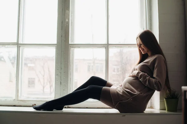 Беременная красивая женщина сидит у окна — стоковое фото