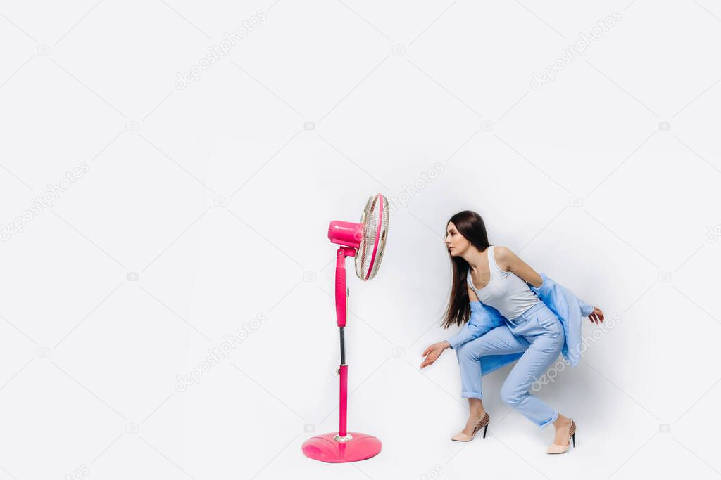 Businesswoman inhales fresh air from a floor fan suffers from the summer heat