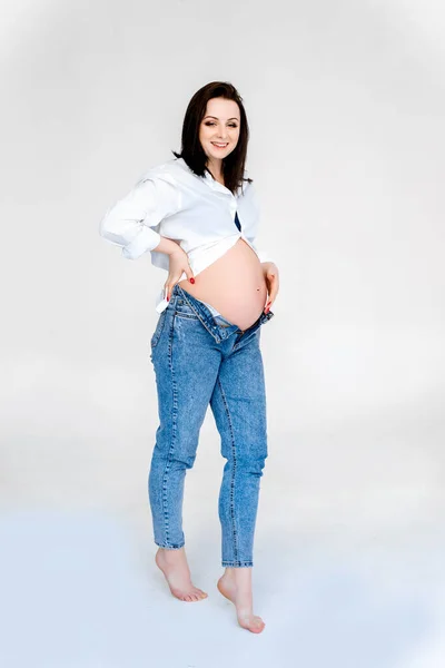Giovane donna incinta è in piedi isolato su sfondo bianco. — Foto Stock