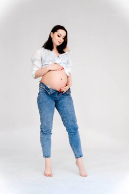 Genç hamile kadın beyaz arka planda tek başına duruyor..