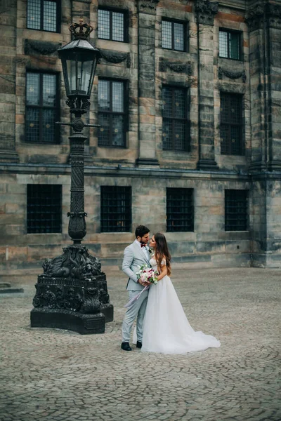 Krásná nevěsta a ženich objímání a líbání na jejich svatební den venku — Stock fotografie