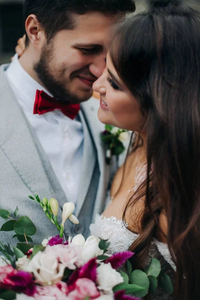 Gyönyörű menyasszony és vőlegény ölelkeznek és csókolóznak az esküvő napján a szabadban — Stock Fotó