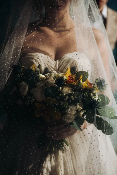 Bride holding beautiful orange wedding flowers bouquet