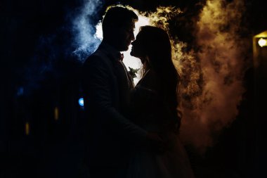 Sokakta dumanlı arka planda öpüşen adam ve kadın..
