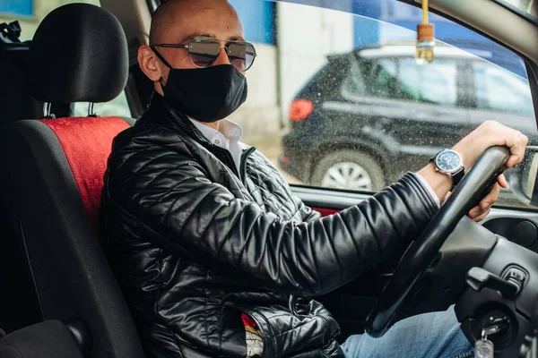 Koruyucu maskeli bir adam araba kullanıyor. Koruyucu maskeli bir adam eczaneye gider..