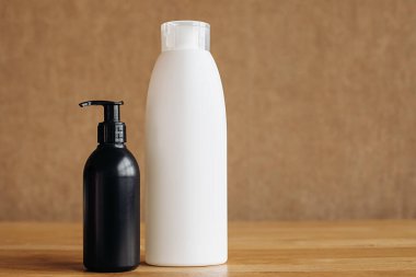 Beyaz ve siyah plastik şişe ve bej arka planda el dezenfektanı. Vücut kozmetikleri .