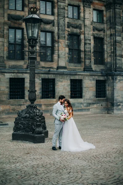 Krásná nevěsta a ženich objímání a líbání na jejich svatební den venku — Stock fotografie