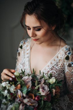 Buketi olan genç ve güzel bir gelin. Boho tarzı, yakın plan portre. Kız bukete bakıyor.