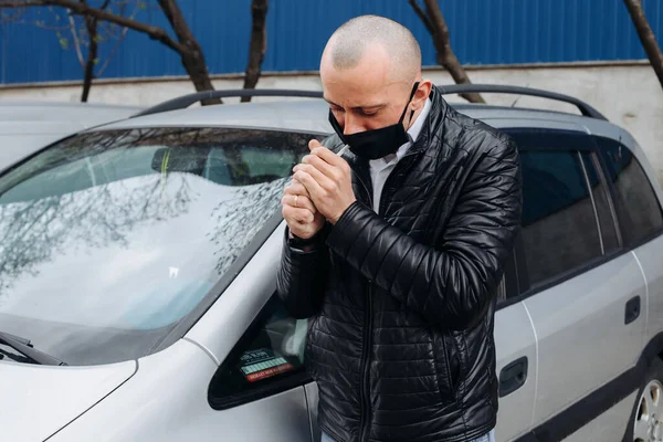 a masked man during the COVID-19 pandemic smokes on the street. Bald man, black