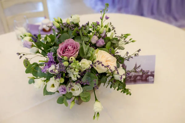 Wedding decor in purple shades . A beautifully decorated holiday table with a beautiful floral arrangement of fresh white roses and purple flowers in an antique vase. wedding dinner, party, festival