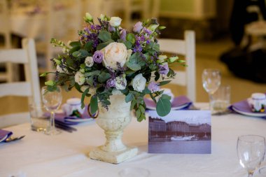 Mor gözlüklü düğün dekoru. Çok güzel dekore edilmiş bir tatil masası. Çiçeklerle süslenmiş taze beyaz güller ve mor çiçekler antika bir vazoda. düğün yemeği, parti, festival