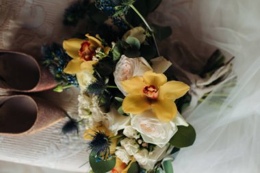 Gelinin sabahı. Düğün konsepti. Düğün detayları: sarı süsen çiçekleri, parlak bej ayakkabılar.