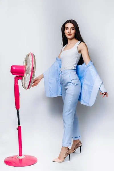 Businesswoman feels hot use a fan in the office struggle with the lack of air conditioning . Isolated on a white background. Wearing a blue business suit . Space for text. Isolated on background.