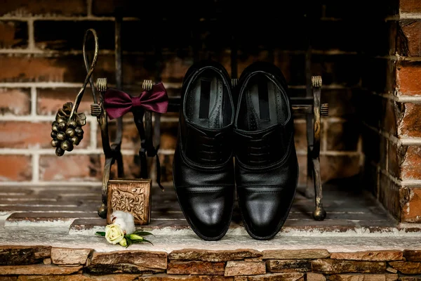 The details of the wedding. Accessories for the groom. Shoes and a red bow tie.