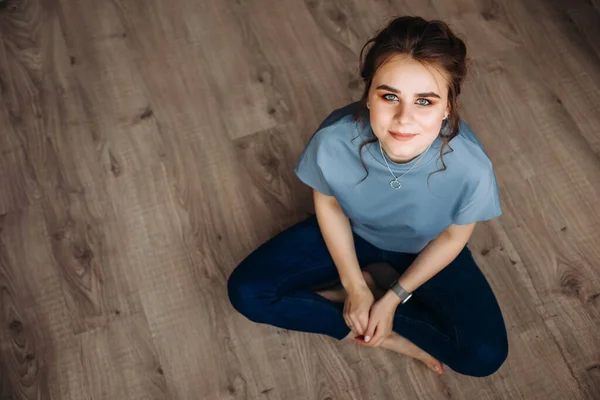 Una Joven Está Sentada Suelo Madera Descalza Mirando Cámara Blusa — Foto de Stock