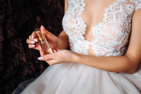 jar of perfume in the hands of the bride. Beautiful wedding manicure.Hands closeup. Wedding morning bride.white lace dress, beautiful neckline